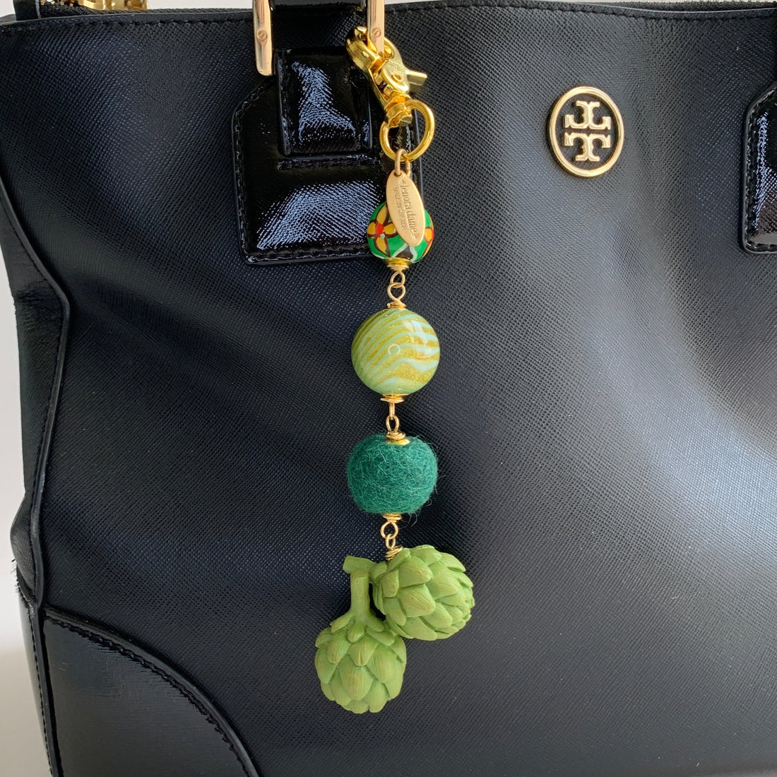 Green bag charm with three green beads and miniature artichokes wire wrapped together.