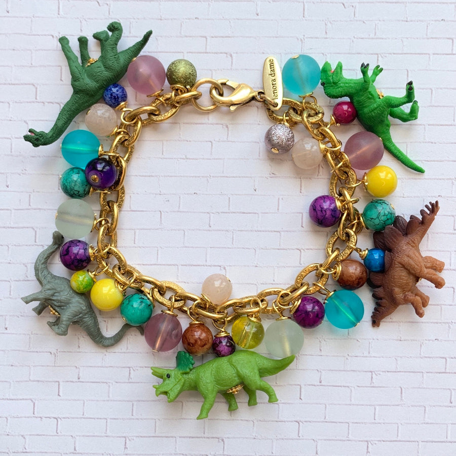 Dinosaur charm bracelet for women. Dinosaur charms on gold charm bracelet with dangling colorful beads.