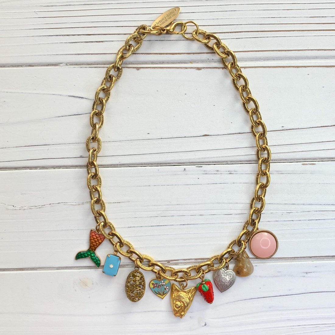 Trendy gold chain charm necklace with a mix of small charms. Gold charm jewelry for women.