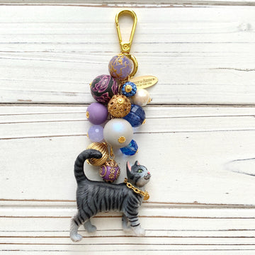 Gray tabby cat bag charm with purple and gold beads. Cat keychain for cat lovers.