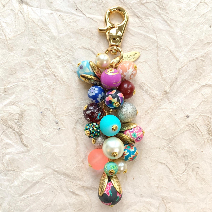 Beaded bag charm for handbags. Gold trigger clasp with long chain filled with a mix of floral beads, sparkly beads and pearls. Colorful purse charm.