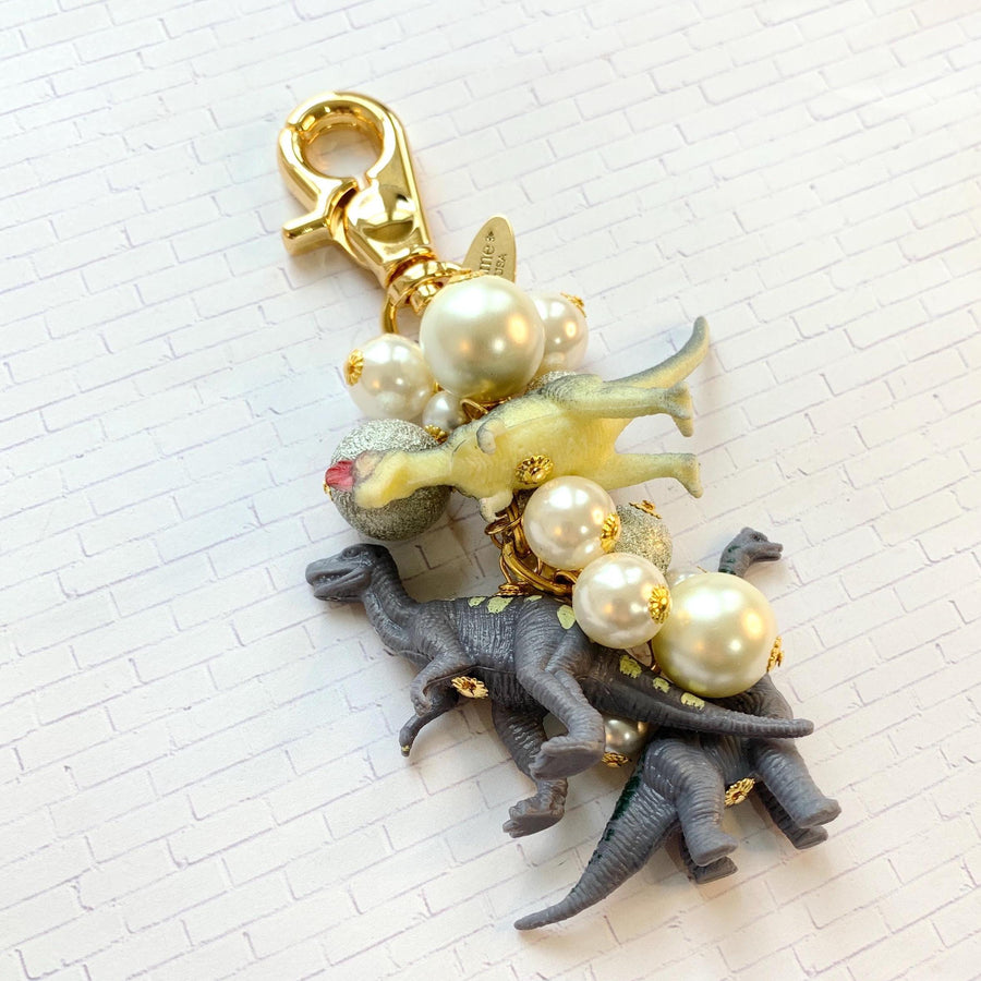 Dinosaur bag charm with grey dinosaur charms, silver beads and pearls on a gold chain with gold trigger clasp. Dinosaur gift idea.