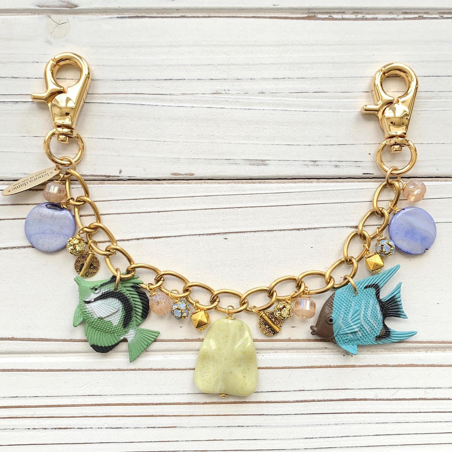 Fish bag chain with blue and green tropical fish charms, round blue beads, and rhinestone ball beads hanging on a gold chain with trigger clasps on each end. Fish bag charm.