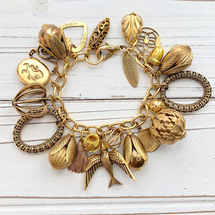 Chunky gold charm bracelet for women. Gold chain filled with variety of interesting gold tone and plated brass charms in assorted shapes and designs.