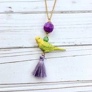 Parakeet pendant necklace for women. Yellow parakeet pendant with purple tassel, green rhinestone beads, purple crackle bead hung on a gold chain.